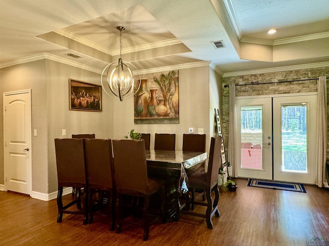 dining space with french doors, a raised ceiling, ornamental molding, and a notable chandelier