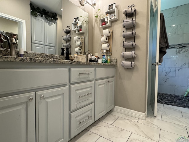 bathroom with a tile shower and vanity