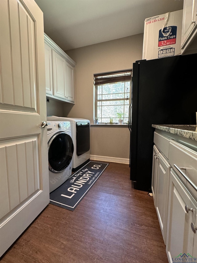 clothes washing area with washer and clothes dryer, cabinets, and dark wood-type flooring