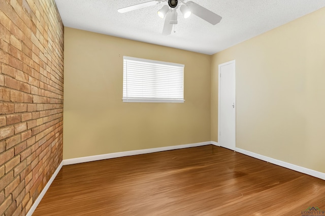 1303 Le Duke Blvd, Longview, TX 75601 - empty room with brick wall, wood finished floors, a textured ceiling, and ceiling fan