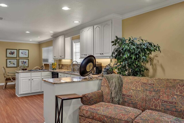 1303 Le Duke Blvd, Longview, TX 75601 - kitchen with a peninsula, light wood finished floors, ornamental molding, light stone counters, and recessed lighting