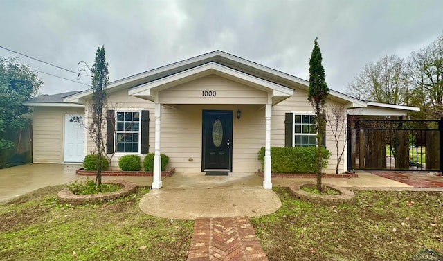 ranch-style home featuring covered porch and a front lawn