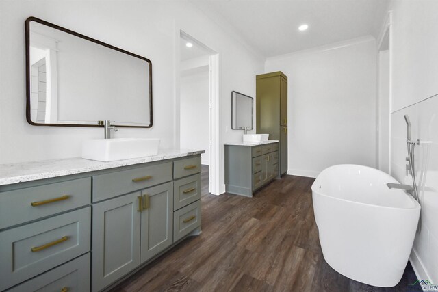 bathroom with hardwood / wood-style flooring, ornamental molding, a tub to relax in, and vanity