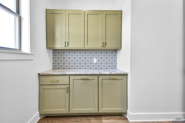 kitchen with light stone counters, decorative backsplash, and wood-type flooring