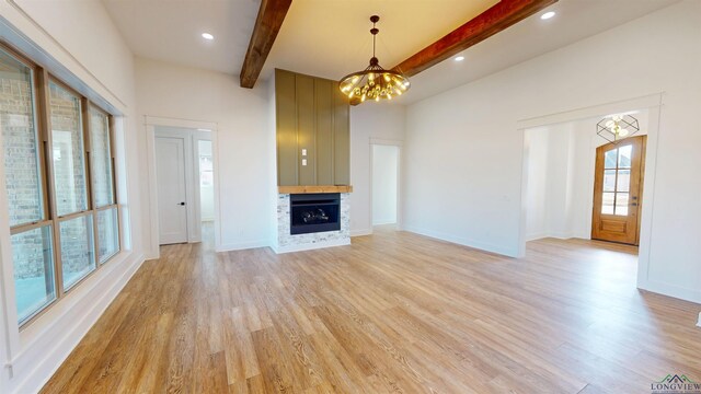 unfurnished living room featuring hardwood / wood-style flooring, a chandelier, and beam ceiling
