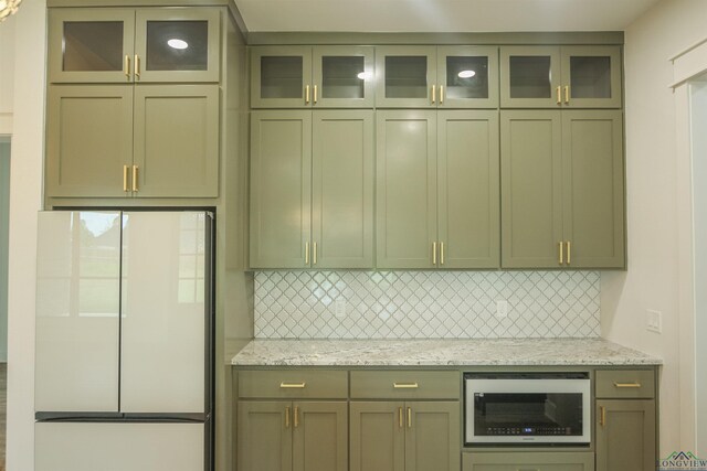 kitchen with stainless steel gas range, sink, light stone counters, hanging light fixtures, and backsplash