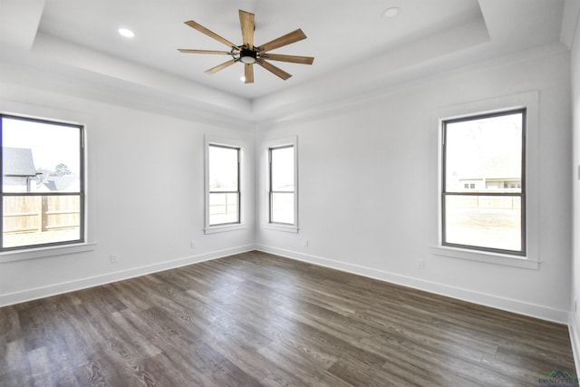 spare room with a raised ceiling, dark wood-type flooring, and ceiling fan