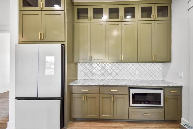 kitchen with light stone counters, light hardwood / wood-style flooring, and white refrigerator