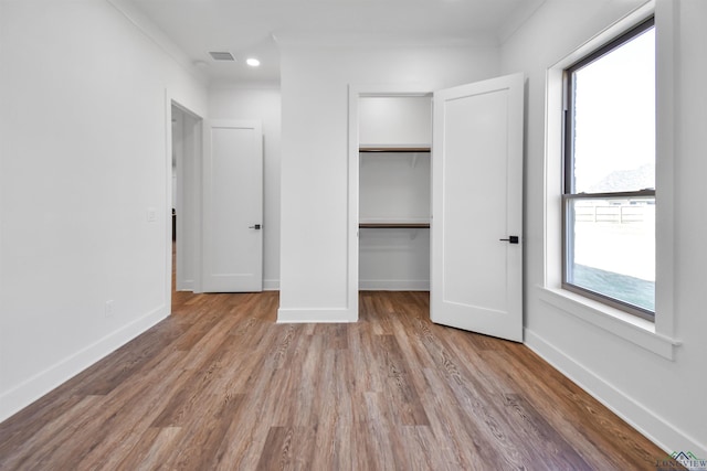 unfurnished bedroom featuring a closet, a spacious closet, and light hardwood / wood-style flooring
