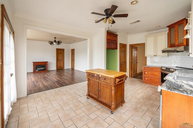 kitchen with tasteful backsplash, butcher block countertops, ceiling fan, and crown molding