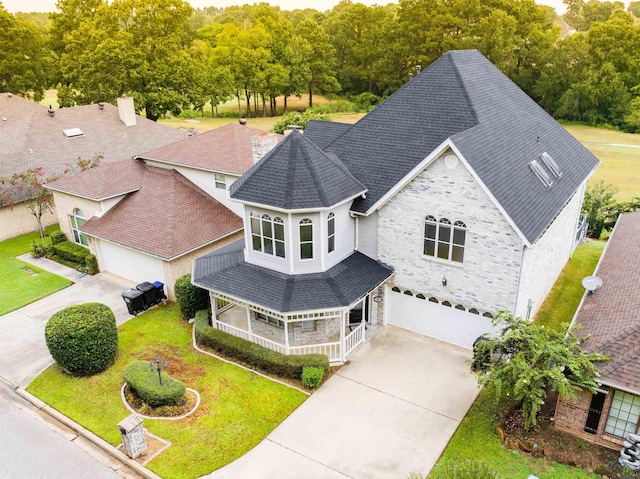 victorian house featuring a front yard, concrete driveway, an attached garage, brick siding, and central AC