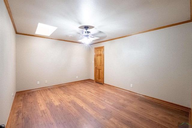 spare room featuring a skylight, light hardwood / wood-style flooring, and ornamental molding