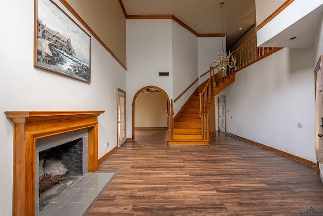 unfurnished living room featuring ornamental molding, dark wood-type flooring, and a towering ceiling