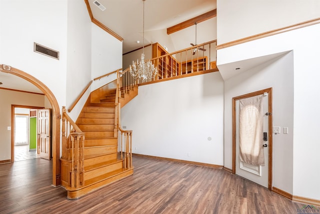 foyer entrance with dark wood-type flooring, a high ceiling, and a notable chandelier