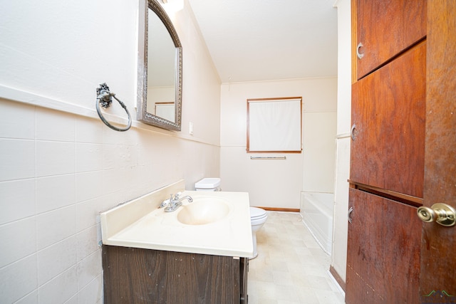 bathroom with vanity, a tub to relax in, and toilet