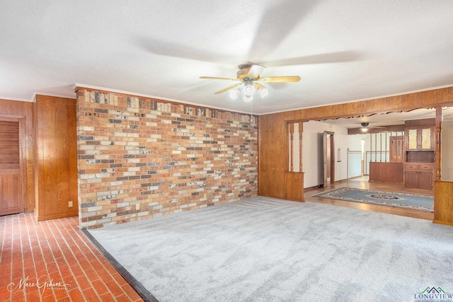 carpeted empty room featuring ornamental molding, a textured ceiling, and wood walls