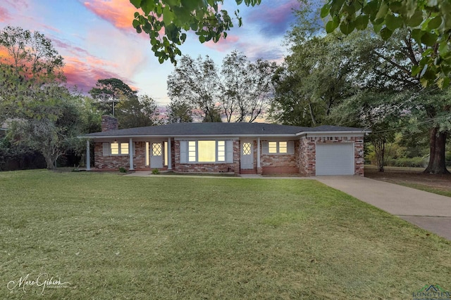 ranch-style house with a garage and a lawn