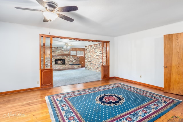 living room with light hardwood / wood-style flooring, a fireplace, and ceiling fan