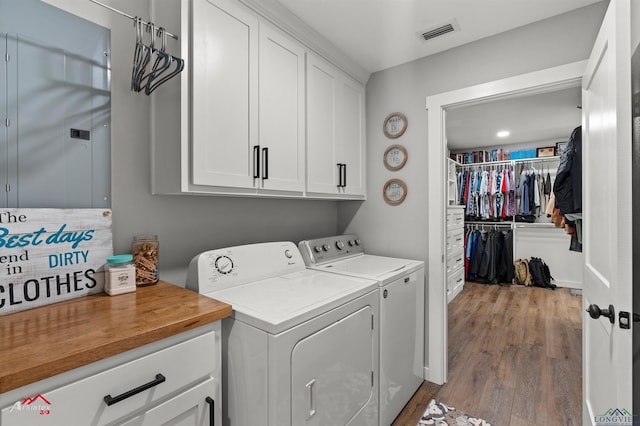laundry room with washer and clothes dryer, light wood finished floors, cabinet space, and visible vents