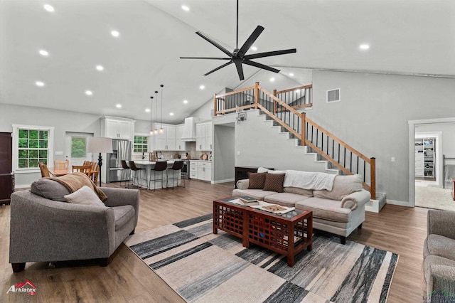 living room with stairs, high vaulted ceiling, visible vents, and wood finished floors