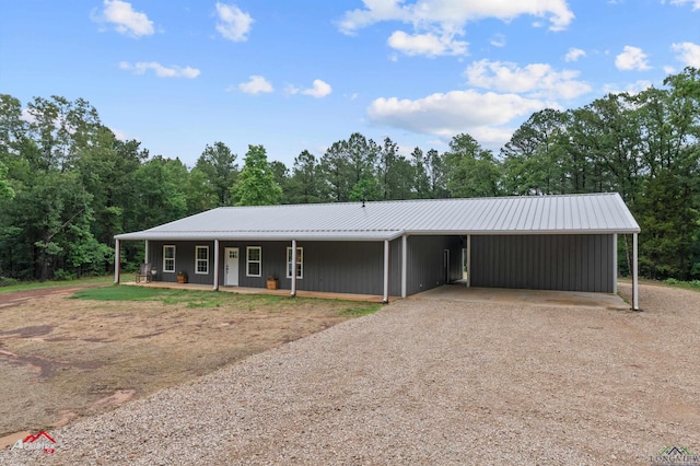 view of front facade with driveway, a porch, metal roof, and a carport