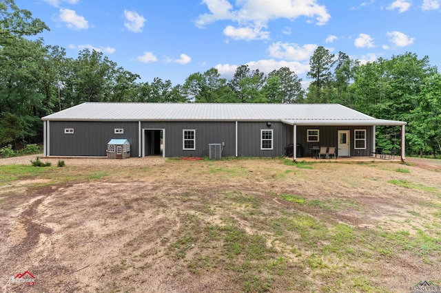 view of front of home with a pole building, metal roof, board and batten siding, central AC unit, and an outbuilding