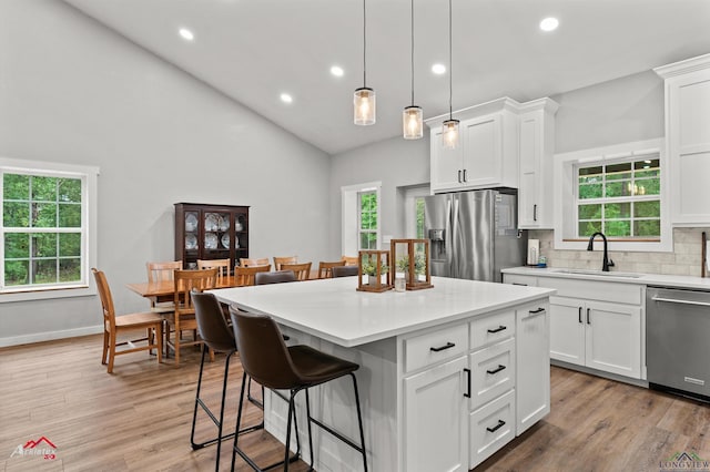 kitchen with high vaulted ceiling, stainless steel appliances, a kitchen bar, and a sink