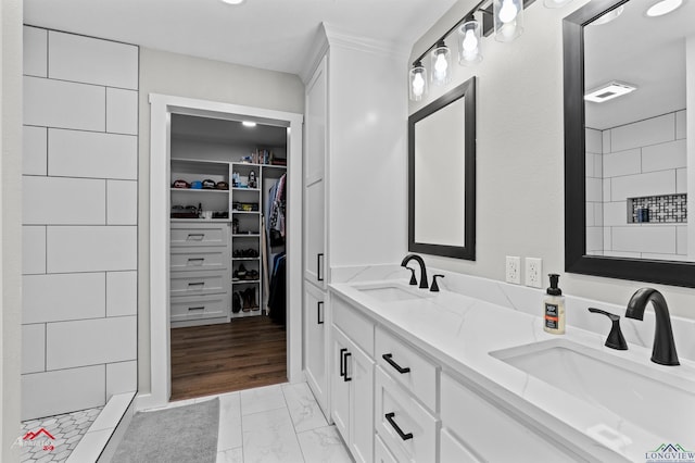 bathroom featuring a sink, double vanity, a walk in closet, and marble finish floor