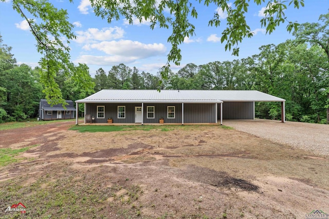 ranch-style house with covered porch, driveway, an attached carport, and metal roof
