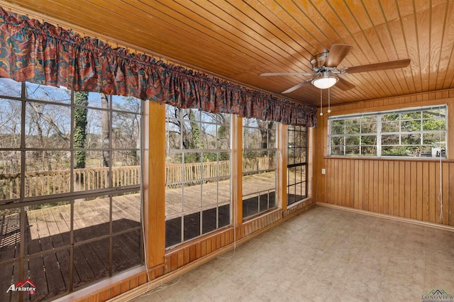 unfurnished sunroom featuring tile patterned floors, wood walls, wood ceiling, and baseboards