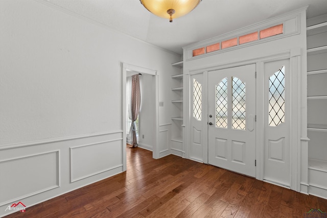 foyer entrance with plenty of natural light, ornamental molding, a wainscoted wall, and wood finished floors