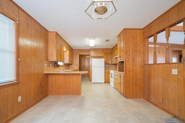 kitchen featuring white appliances, wooden walls, kitchen peninsula, and a textured ceiling