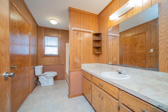 bathroom featuring vanity, a textured ceiling, wooden walls, and toilet