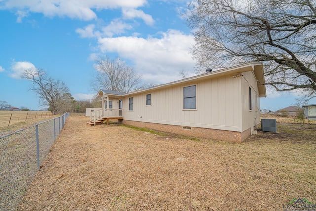 rear view of property featuring cooling unit and a lawn