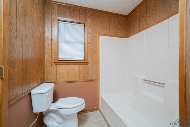 bathroom with a bath, a textured ceiling, tile patterned floors, toilet, and wood walls