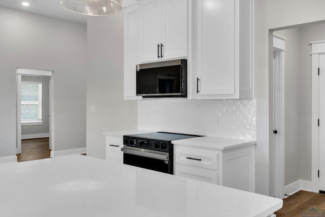 1513 Wellington Ln, Longview, TX 75605 - kitchen with black microwave, electric stove, light countertops, tasteful backsplash, and white cabinetry