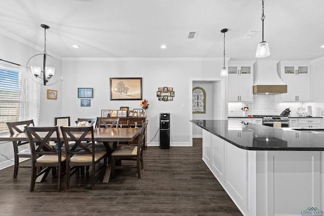 kitchen featuring ornamental molding, stainless steel range, custom range hood, decorative light fixtures, and white cabinetry