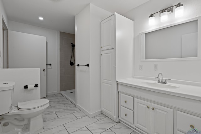 bathroom with tiled shower, vanity, and toilet