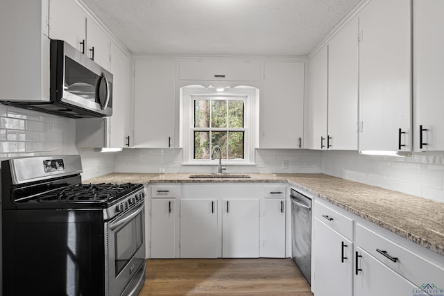 kitchen featuring a textured ceiling, stainless steel appliances, tasteful backsplash, white cabinets, and sink