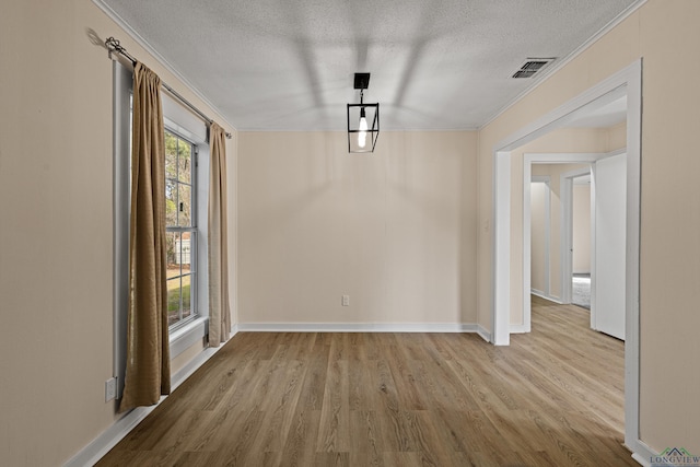 interior space featuring light hardwood / wood-style floors, a textured ceiling, plenty of natural light, and crown molding