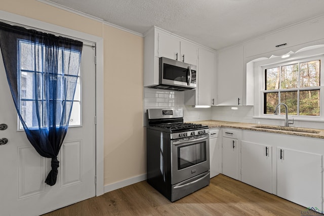 kitchen featuring stainless steel appliances, decorative backsplash, sink, light hardwood / wood-style flooring, and white cabinetry