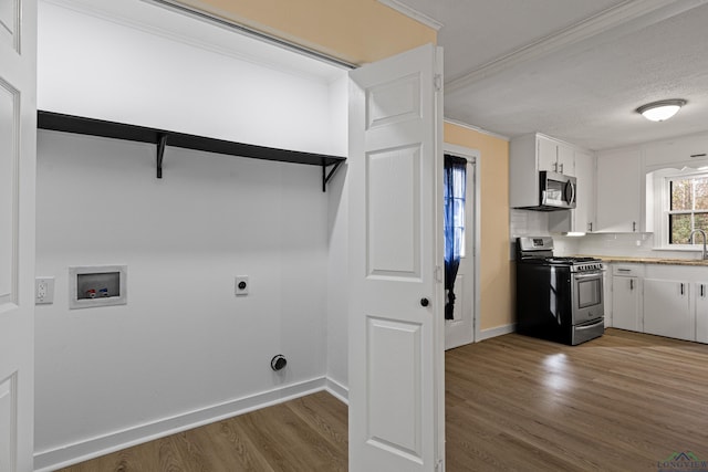 laundry area with washer hookup, a textured ceiling, hookup for an electric dryer, wood-type flooring, and sink