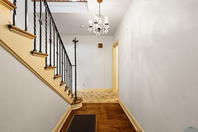 interior space featuring a chandelier, wood finished floors, visible vents, baseboards, and stairs