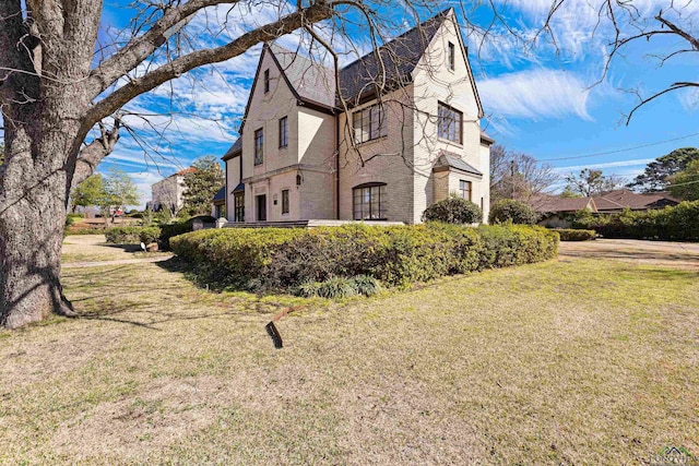 view of side of property with a lawn and brick siding