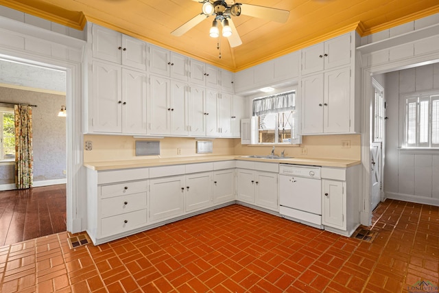 kitchen with white dishwasher, brick floor, a sink, white cabinetry, and light countertops