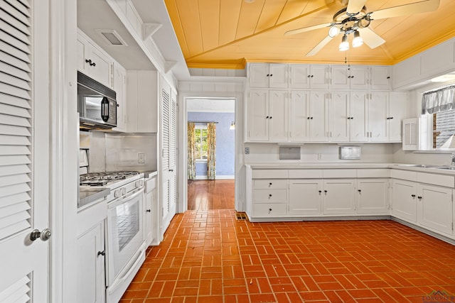 kitchen featuring brick floor, white cabinetry, white gas range, and black microwave