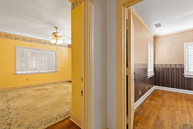 corridor featuring hardwood / wood-style flooring, visible vents, wainscoting, and wallpapered walls