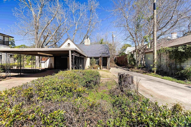 view of front of property featuring a chimney, an attached carport, and concrete driveway