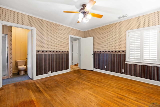 unfurnished bedroom featuring visible vents, baseboards, wallpapered walls, wood-type flooring, and crown molding