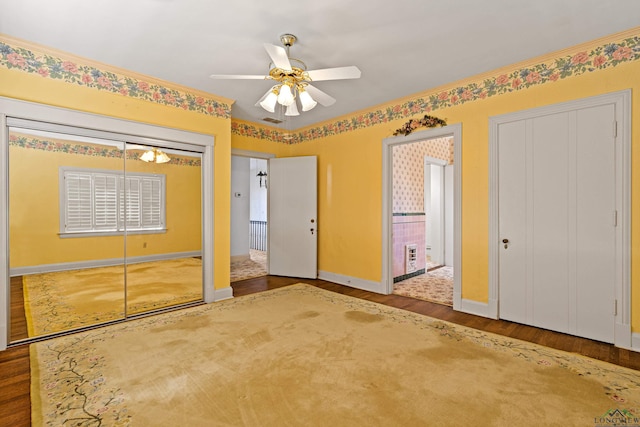 unfurnished bedroom featuring a ceiling fan, baseboards, visible vents, and wood finished floors